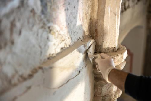Close-up of Repairing Damaged Wall with Trowel in Antique Chapel - stock photo